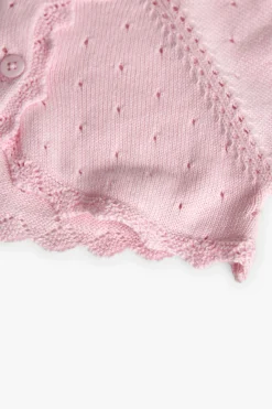 Bolero in maglia per neonata di colore rosa.