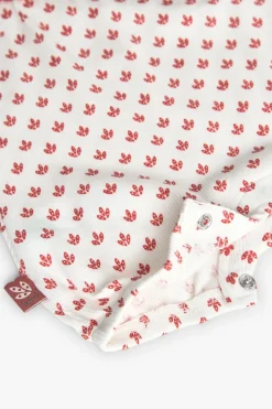 Pagliaccetto in maglia per neonata di colore bianco con motivo di fiori rossi.